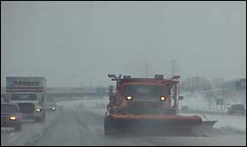 Photo of a snowplow and other vehicles on a highway.
