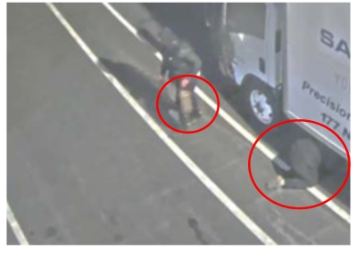 Still image of surveillance footage showing masked man stealing catalytic converter from a truck. 