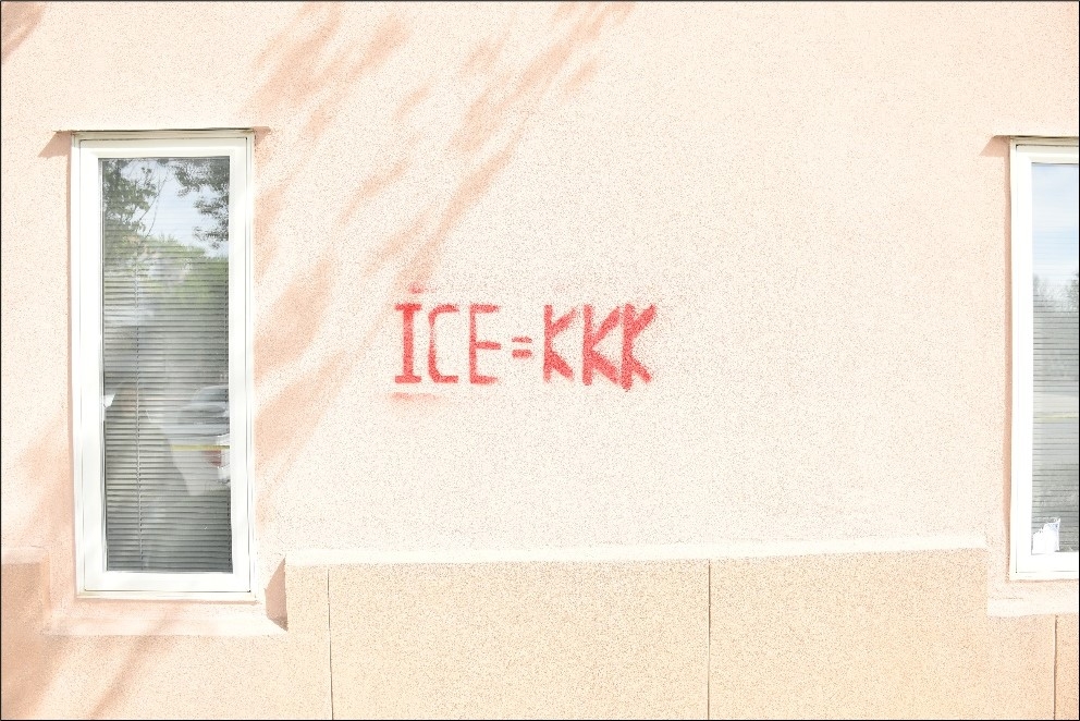 Exterior building façade with ICE = KKK spraypainted in red.