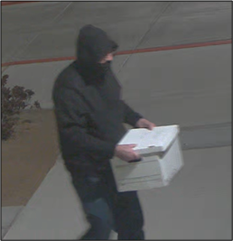 Individual in dark clothing carrying a white box.