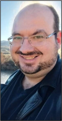 Bald man with glasses smiling.