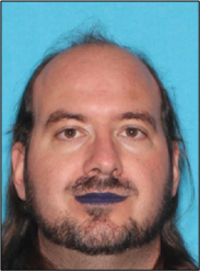 A person with a beard against a blue background.